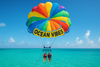Parasailing over turquoise waters with colorful parachutes against a blue sky, showing the thrill of Ocean Vibes parasailing adventures in Turks & Caicos